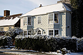 Bemalte Hausfassade mit Schneefall auf Hecke in Tenterden, Kent, England, UK