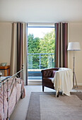 Brown leather armchair at window in bedroom of modern home Bath Somerset, England, UK