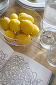 Bowl of lemons and an open colouring book on table in Smarden home Kent England UK