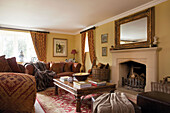 Polstersofa und Couchtisch aus Holz im Wohnzimmer mit vergoldetem Spiegel auf dem Kaminsims in einem Haus in Smarden, Kent, England, UK