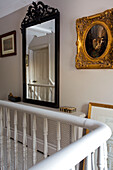 Weiß gestrichenes Geländer mit schwarz gerahmtem Spiegel auf dem Treppenabsatz in einem Haus in Kent England UK