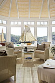 Wicker chairs with model boats in conservatory of Dartmouth home, Devon, UK