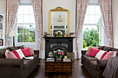 Vergoldeter Spiegel auf dem Kaminsims mit rosa Kissen auf dem Sofa im Wohnzimmer des Hauses Kilndown, Cranbrook, Kent, England, UK