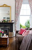 Pink cushions on sofa with wooden coffee table drawer unit in living room of Kilndown home Cranbrook Kent England UK