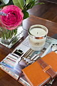 Scented candle and brown leather notebook with pink rose on wooden coffee table in Kilndown home Cranbrook Kent England UK