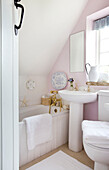 White pedestal basin and bathtub in pick bathroom of Worth Matravers cottage Dorset England UK