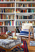 Stuhl und Hocker mit Büchersammlung in einem Strandhaus in Emsworth, Hampshire, England UK