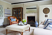 Tan leather armchair and cabinets with tray on ottoman footstool in Bishops Sutton living room Alresford Hampshire England UK