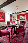 Pink velvet upholstered dining chairs in red dining room of Bishops Sutton home Alresford Hampshire England UK