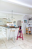 Pink barstool at kitchen island in white fitted kitchen of Bishops Sutton home Alresford Hampshire England UK