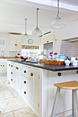 Rosa Barhocker an Kücheninsel in weißer Einbauküche in Bishops Sutton Haus Alresford Hampshire England UK