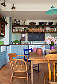 Bemalter Stuhl mit Holztisch und offenem Regal in der Küche eines Hauses in Hackney London England UK