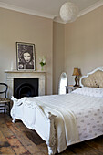 White double bed with original fireplace and oriental photographic print in Hackney home London England UK