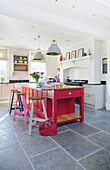 Bright pink kitchen island with flagstone flooring in Woodchurch home Kent England UK