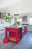 Bright pink kitchen island with flagstone flooring and artwork display in Woodchurch home Kent England UK