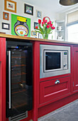 Stainless steel oven in pink island unit with artwork display in Woodchurch kitchen Kent England UK
