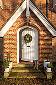 Boots on doorstep with Christmas wreath on front door of Warehorne rectory built in 1829 Kent UK