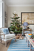 Sessel und Weihnachtsbaum mit blau-weiß gestreiftem Teppich im Pfarrhaus von Warehorne, Kent, Großbritannien