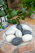 Kitchen diner detail with carved black white and grey stone eggs nesting in a wooden board Oxfordshire UK