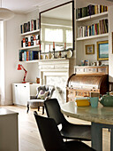 Large rectangular mirror above fireplace with bookshelves in open plan living and dining room of London home England UK