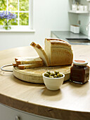 Sliced bread and olives on wooden kitchen worktop Nottinghamshire home England UK