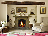 Armchair at lit fireplace in living room of Nottinghamshire home England UK