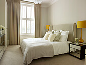 Yellow bedside lamps on mirrored cabinets in bedroom of Little Venice townhouse London England UK