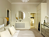 Circular mirror with mirrored sideboard in bedroom of Little Venice townhouse London England UK