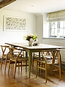 Roses in vase on kitchen table with chairs in West Sussex farmhouse, England, UK