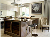 Black leather barstools at wooden island unit in London townhouse kitchen, UK