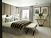 Calla lilies on console in bedroom with striped fur blanket, London townhouse, UK
