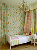 Trennwand aus geblümtem Stoff und Einzelbett in einem Mädchenzimmer in einem Londoner Stadthaus, UK