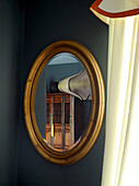 Holzschrank in einem ovalen Spiegel in einem Londoner Stadthaus, UK