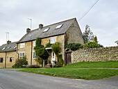 Oxfordshire stone cottage with climbing plant above porch, England, UK