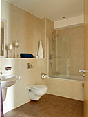 Cream tiled bathroom with shower screen in Manchester home, England, UK