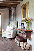 Floral patterned armchair and architectural salvage in timber framed Kent cottage, England, UK