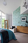 Silberner Tierkopf in einem Schlafzimmer in Cambridgeshire mit türkisfarbener Tagesdecke und gemusterter Tapete UK