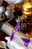 Christmas cracker and lit candle with silver metallic baubles in Kent home, England, UK