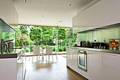 Open plan galley kitchen and table with view to back garden of contemporary London home, England, UK