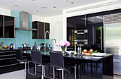 Black and turquoise kitchen with upright stainless steel fridge in Hendon home London UK