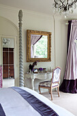 Ornate gilded mirror above dressing table in classic bedroom