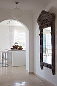 Carved antique mirror in hallway with view through arched doorway to kitchen, holiday villa, Republic of Turkey