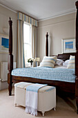 Dunkles Holzbett mit hellblauer Steppdecke in einem Londoner Haus UK