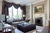 Cut flowers on ottoman with fabric pelmet window detail in contemporary London townhouse, UK