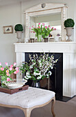 Cut flowers and ottoman at fireplace of Sussex home UK