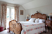 Carved wooden bed with patchwork quilt in Sussex home UK