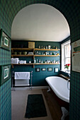 Blick durch eine gewölbte Tür zum Badezimmer eines Hauses in Suffolk mit Regalen mit Toilettenartikeln UK