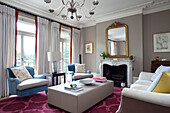 Matching blue armchairs with leather ottoman in living room with pink carpet, contemporary London home, UK