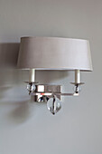 Muted metallic lampshade on silver wall scone in contemporary London home, UK