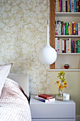 Recessed book shelves and pendant light at bedside in contemporary London home, UK